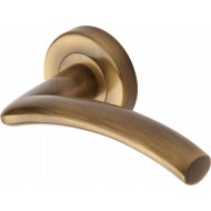 Centaur Curved Lever Handles on Rose in Antique Brass